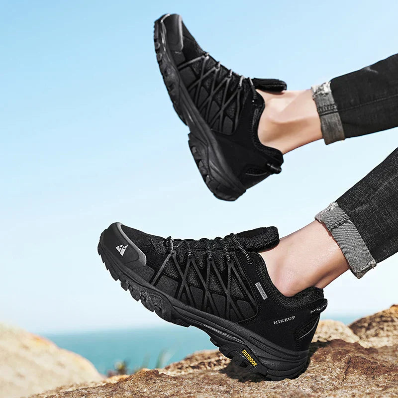 Black men's hiking shoes with durable construction and superior grip, worn outdoors on rocky terrain