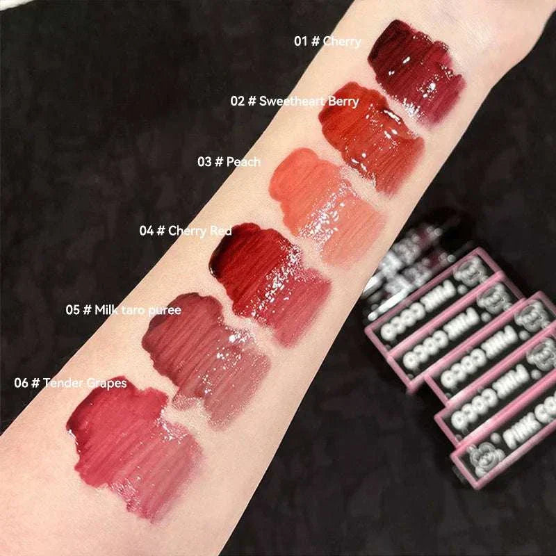 PINKCOCO Bear Doodle Mirror Lip Glaze swatches on arm showing six glossy shades including Cherry, Sweetheart Berry, Peach, Cherry Red, Milk taro puree, and Tender Grapes
