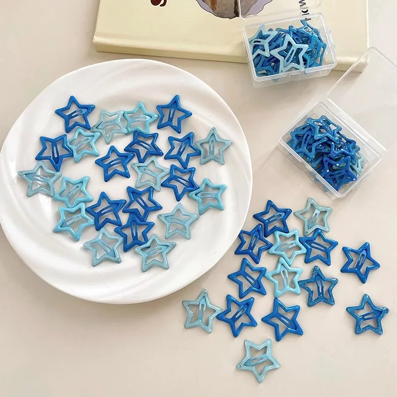 Set of colorful kawaii star-shaped hair barrettes in blue shades on a white plate and clear plastic boxes