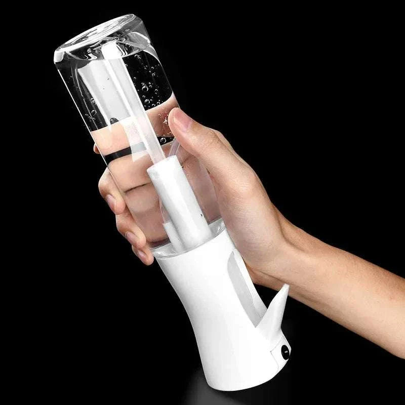 Hand holding a clear refillable high pressure mist spray bottle with white ergonomic trigger against black background