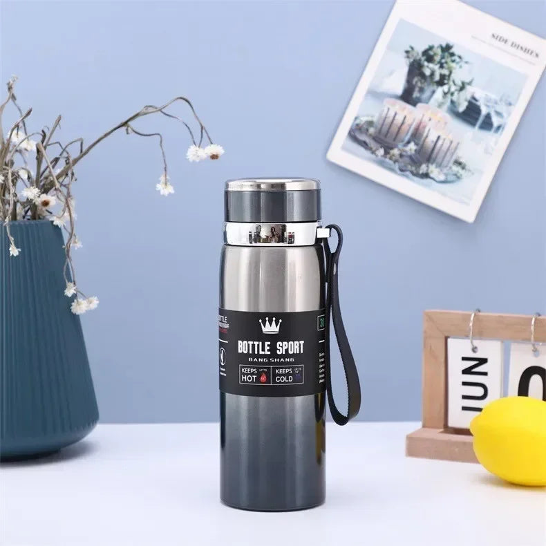1L hot and cold stainless steel thermos bottle with vacuum insulation and carrying strap on table with decorative items in background