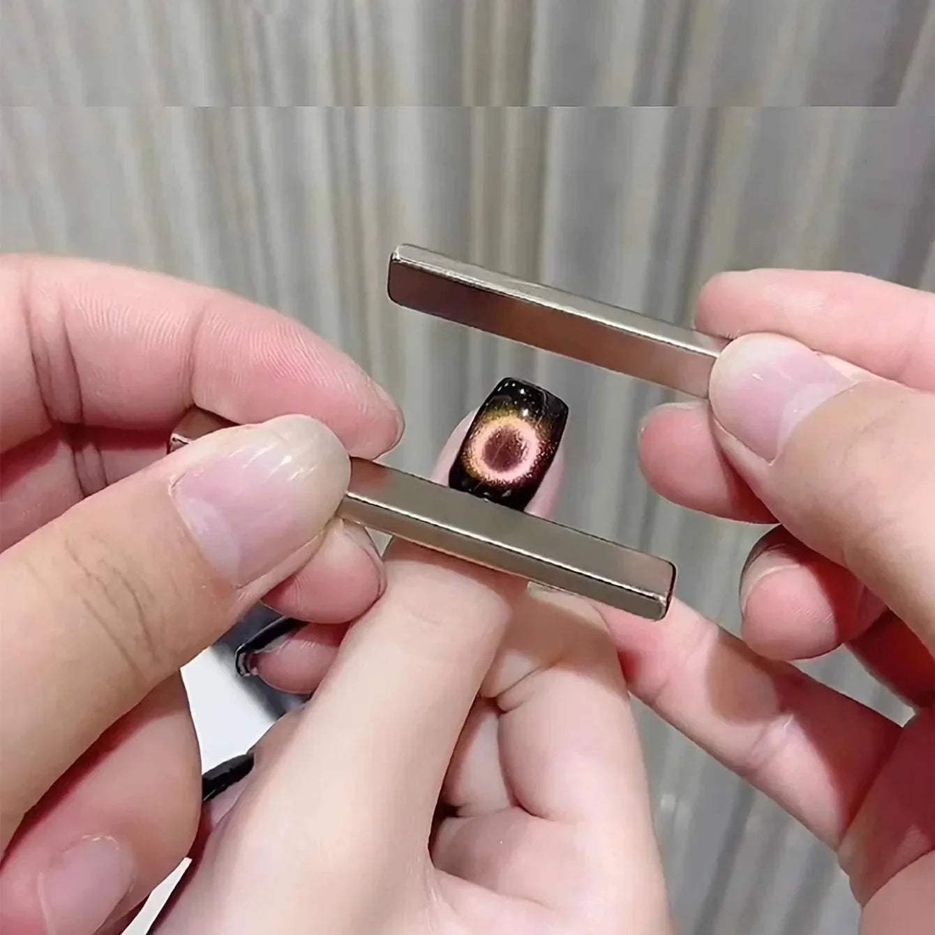 Hands using Nail Art Magnetic Pen to create 3D cat eye effect on black gel nail polish