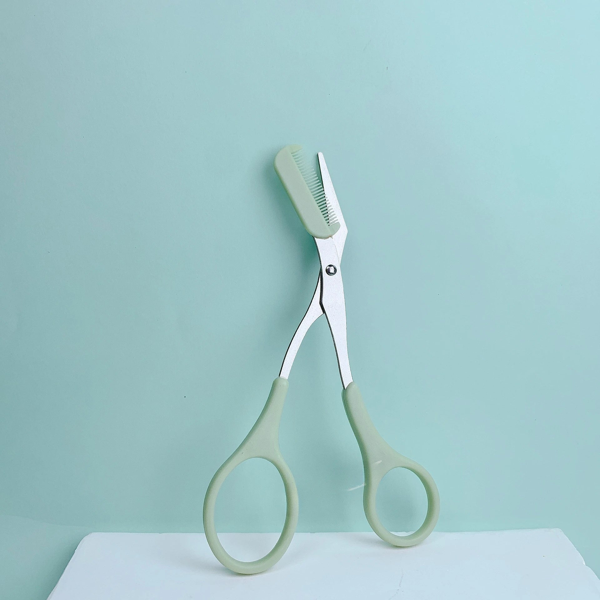 Pink eyebrow trimming scissors with built-in comb