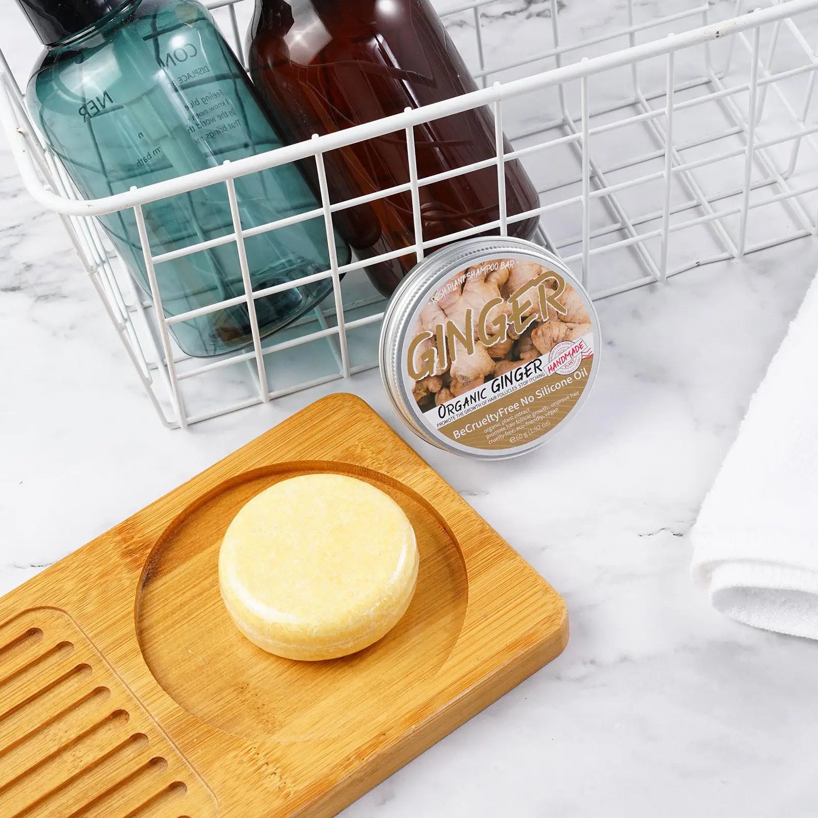 Ginger Polygonum Soap shampoo bar on wooden soap dish with toiletries in wire basket on marble surface