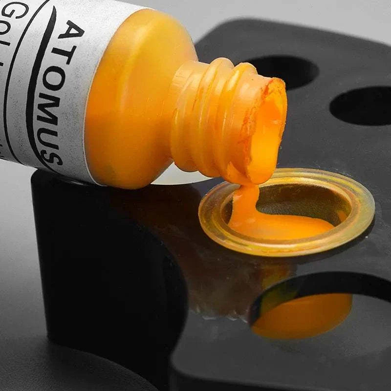 Transparent disposable plastic ink cup filled with orange tattoo pigment on a black holder tray