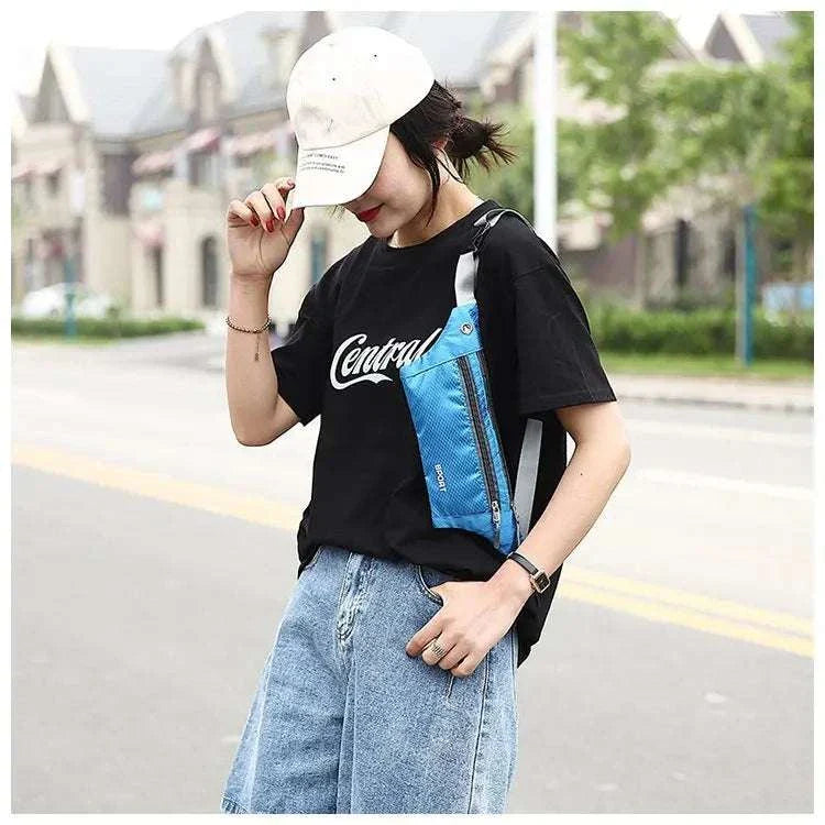 Woman wearing a blue nylon waist and chest bag over black t-shirt and denim shorts outdoors