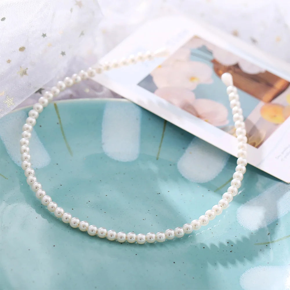 Modyle Full Pearl Hairband with elegant floral design and elastic fit on blue plate