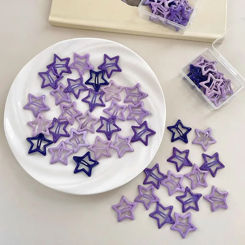 Colorful Kawaii star-shaped barrettes in purple tones on white plate and containers