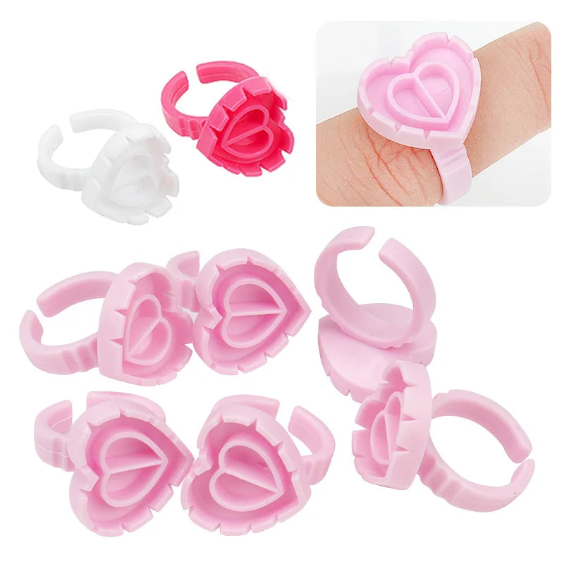 Heart-shaped disposable glue ring cups for lash extensions and tattoo pigments, wearable and hygienic plastic adhesive holders, bulk pack of 100
