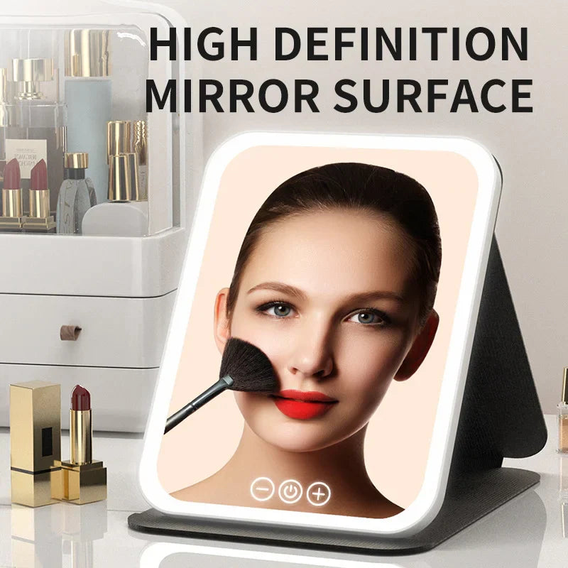 LED dimmable makeup mirror with high definition surface, adjustable brightness, and 3 color light modes, shown reflecting a woman applying makeup with a brush.