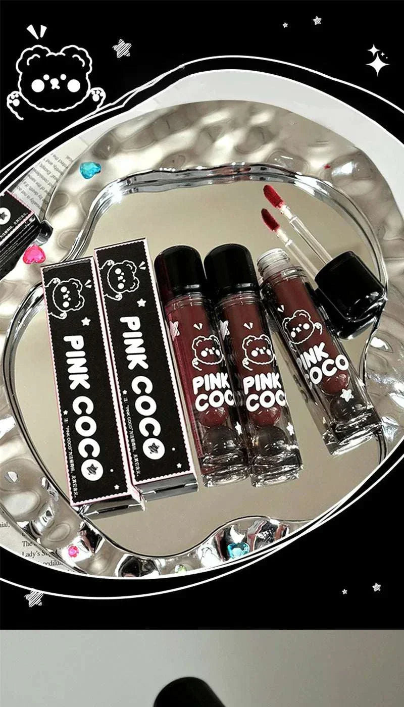 PINKCOCO Bear Doodle Mirror Lip Glaze tubes with black bear doodle packaging on reflective silver tray
