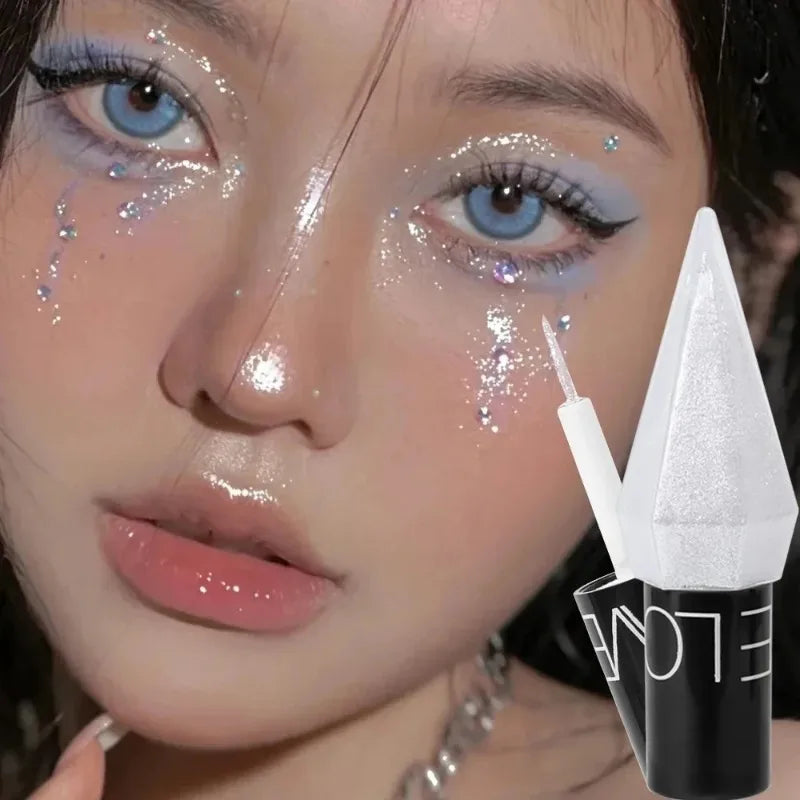 close-up of woman wearing diamond shiny eye liners and eyeshadow with glitter accents and applicator brush against dark background