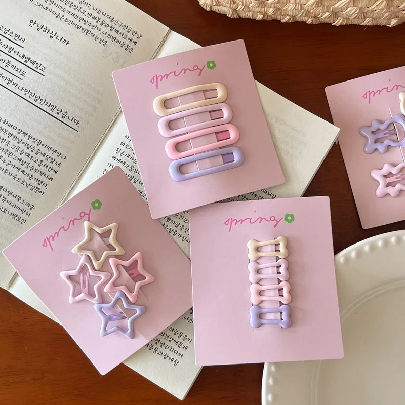 Cute colorful geometric mini hair clips set in pastel pink, purple, and cream on pastel pink cards