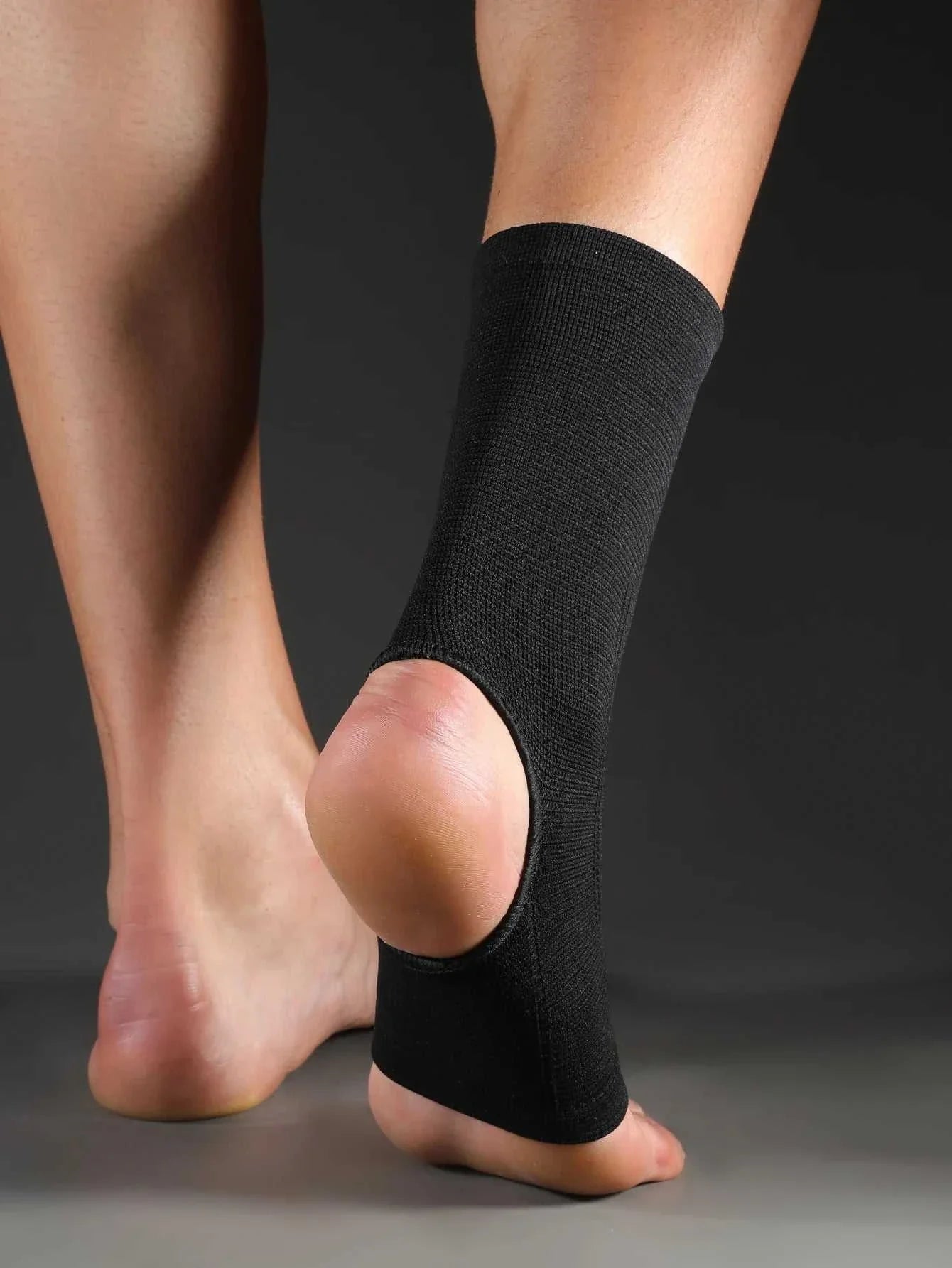 Black elastic breathable ankle support brace worn on foot for compression and injury prevention