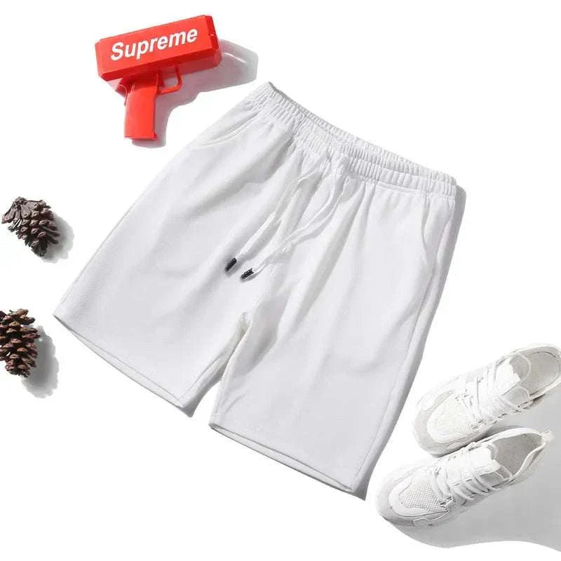 White 2025 NEW Fitness Sports Shorts for men with elastic waistband displayed with white sneakers and pine cones on white background