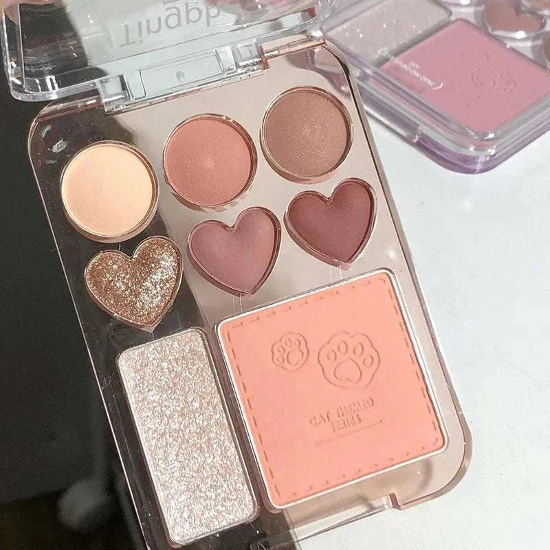 8-Color pink and orange eyeshadow palette with heart-shaped pans, blush, and highlighter in a transparent compact.