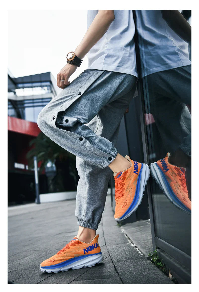 Orange unisex running shoes with carbon plate air cushion technology worn with gray joggers outdoors