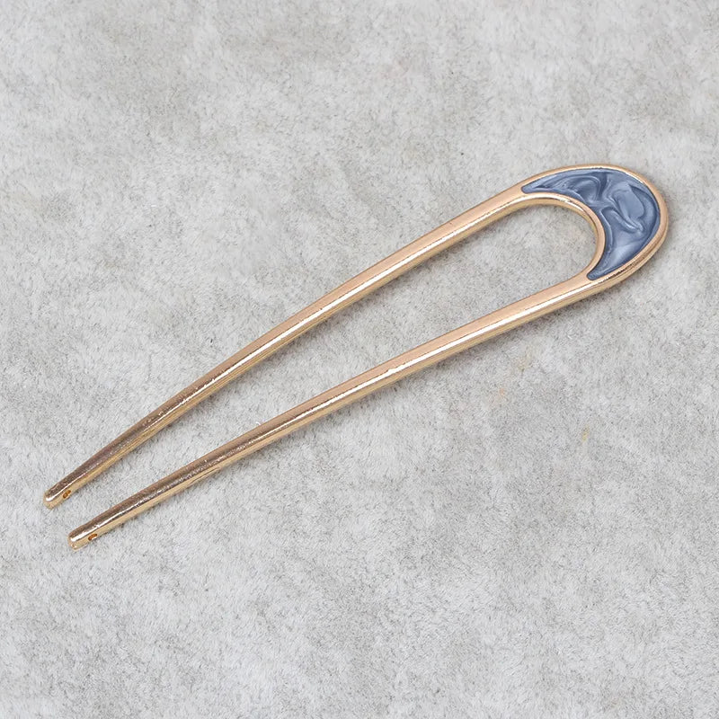 Pearl U-shaped hairpin with metallic shell detail on gray background