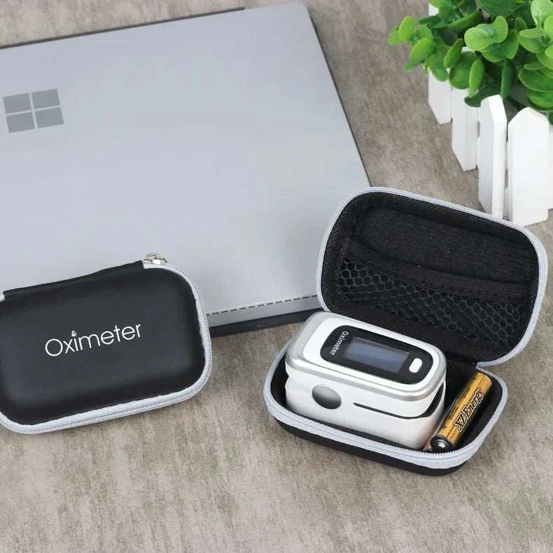 Compact black oximeter case with digital fingertip pulse oximeter and battery inside on a wooden surface.