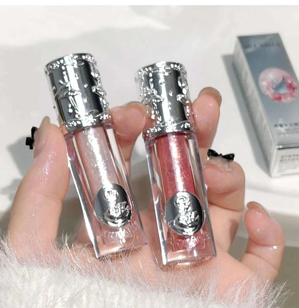 Two Balletism Liquid Eyeshadow bottles with fine shimmer highlight held in hand showing elegant silver caps and clear packaging.