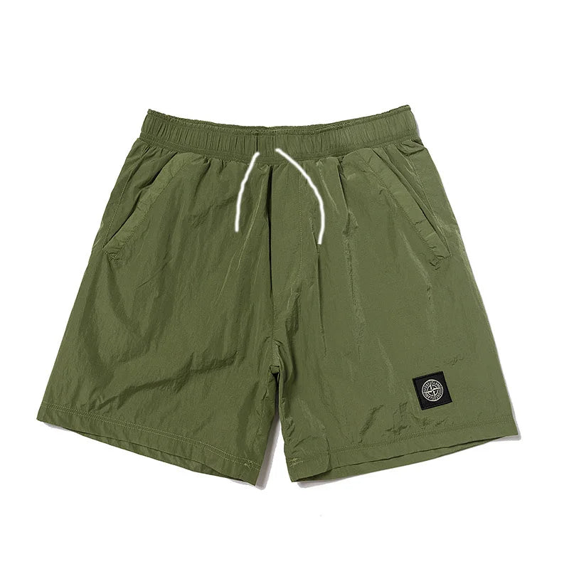 Olive green men's sports casual shorts with elastic waistband and retro logo patch, quick-dry breathable fabric.