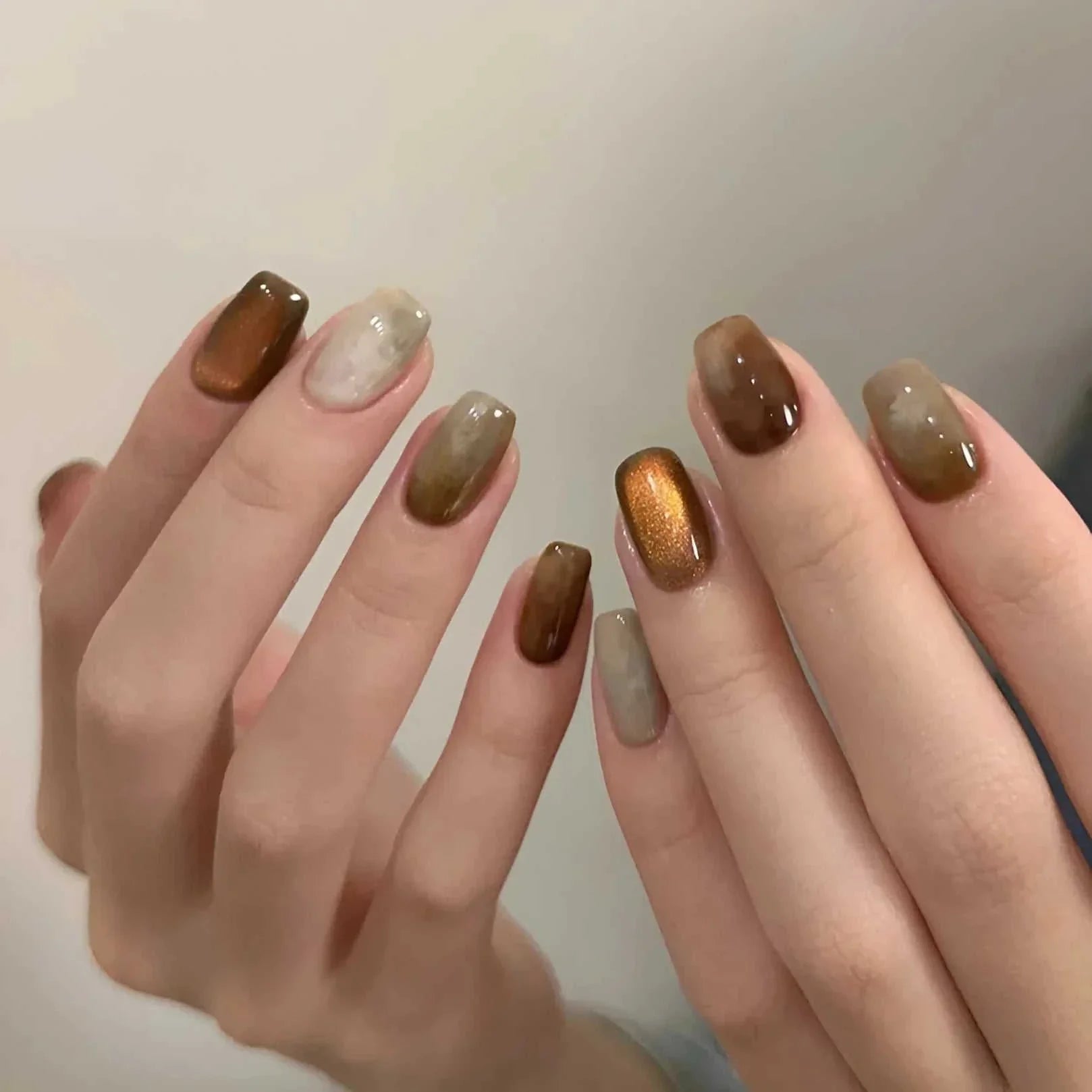 Hands with brown and beige cat eye gel nail art manicure using Nail Art Cat Eye Gel Magnetic Pen