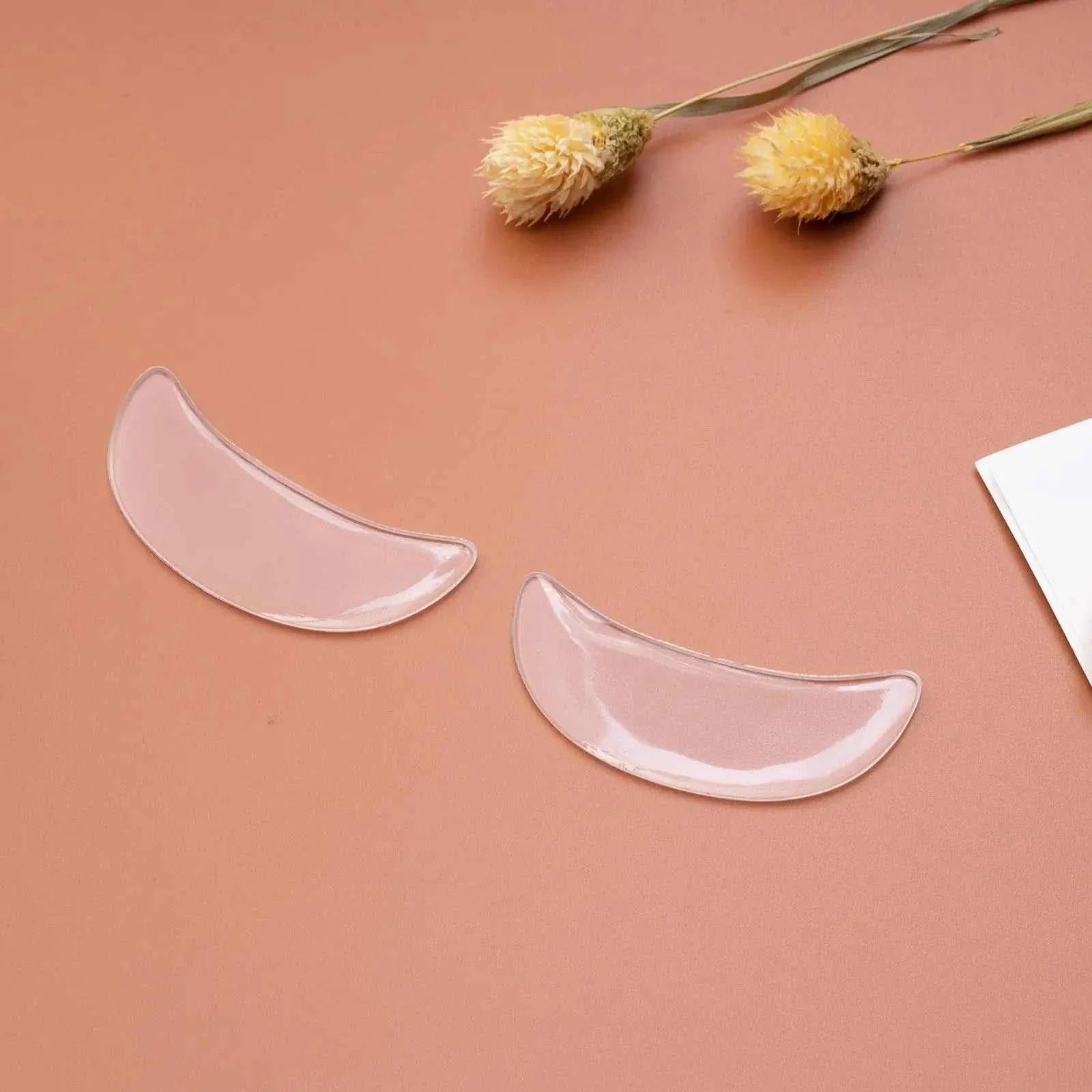 Reusable anti-wrinkle forehead patches made of soft, medical-grade silicone on a brown surface with dried flowers nearby