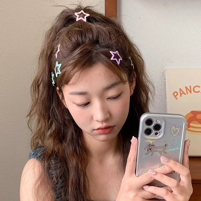 Young woman with colorful kawaii star barrettes in curly hair holding a smartphone