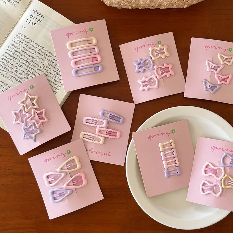 Cute colorful geometric mini hair clips set for girls in pastel shades on pink cards displayed on wooden table