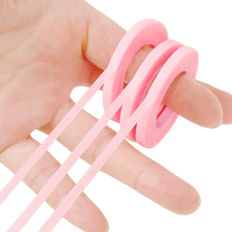 Pink micropore eyelash extension tape rolls held on hand for lash application