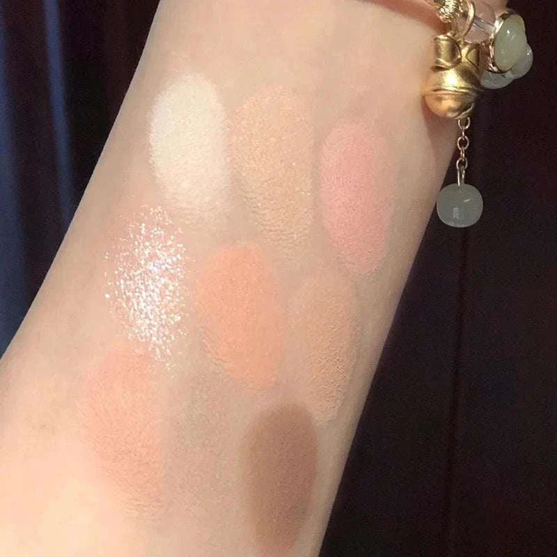 Swatches of Black Pink Smoky Eye shadow palette shades on arm showing matte and pearlescent finishes in soft pink, peach, and brown tones.