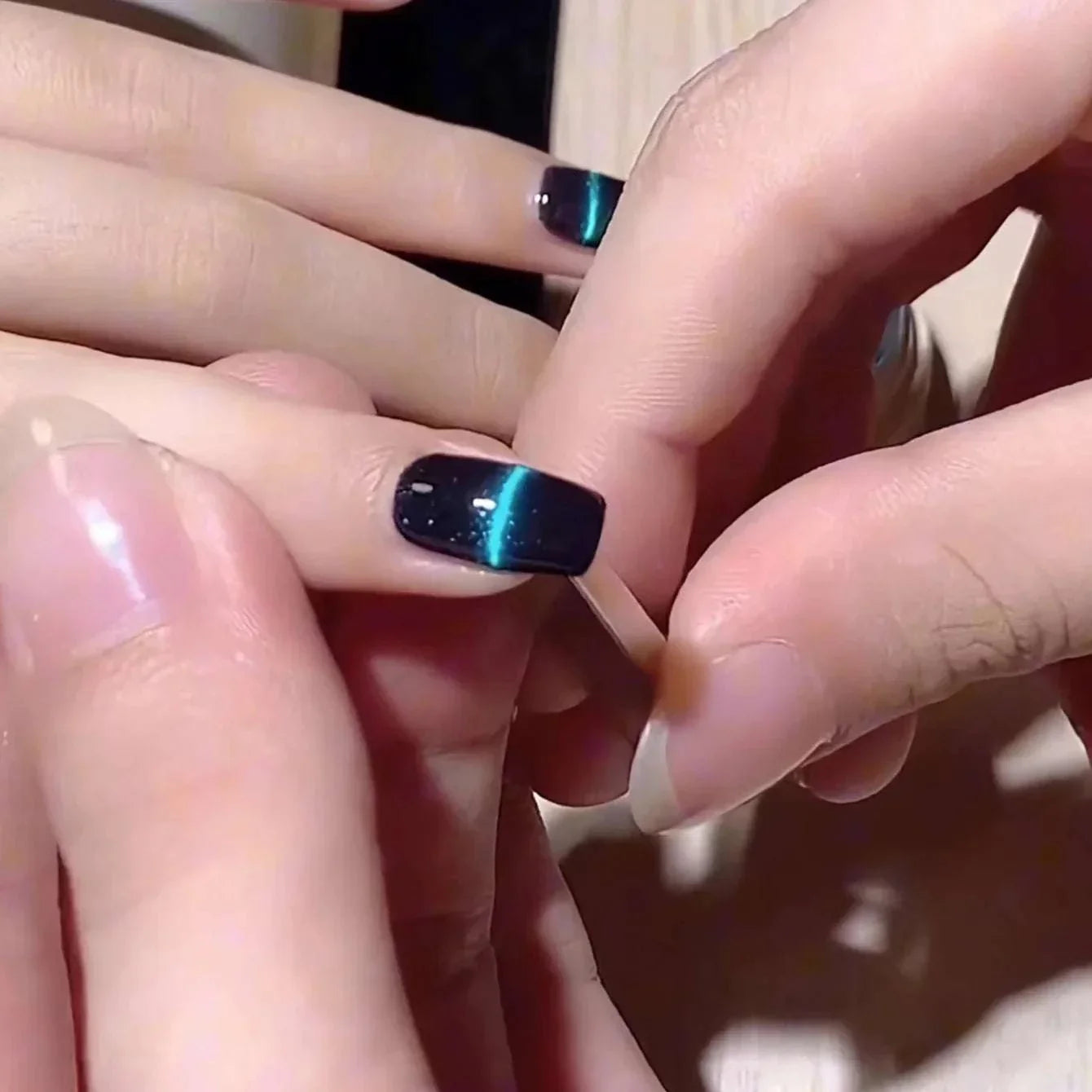 Close-up of hands using a Nail Art Magnetic Pen to create a 3D cat eye effect on dark gel polish nails.