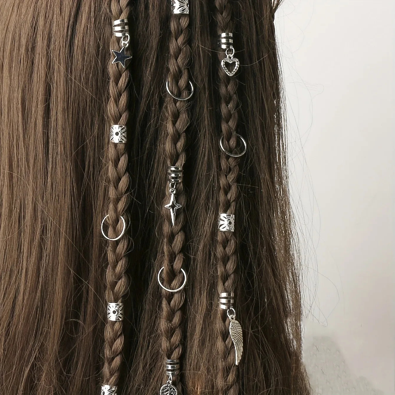 Close-up of braids decorated with silver alloy braid hair rings from a 45-piece set, featuring boho dreadlock jewelry charms like stars, hearts, and wings.