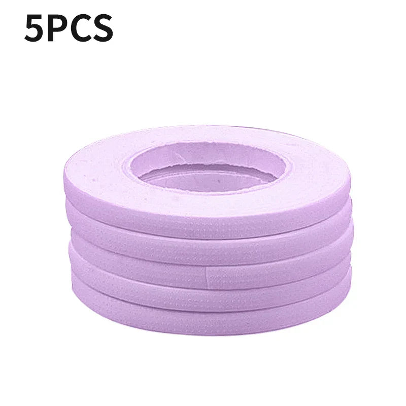Stack of five pink micropore eyelash extension tape rolls for lash application