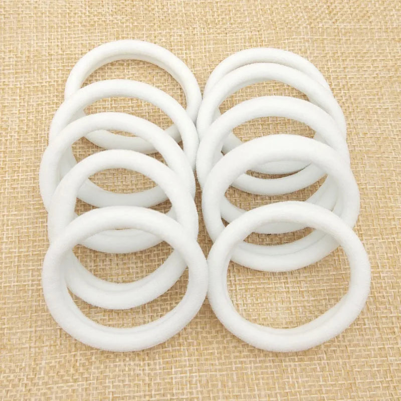 Set of white nylon scrunchies on woven background for hair styling