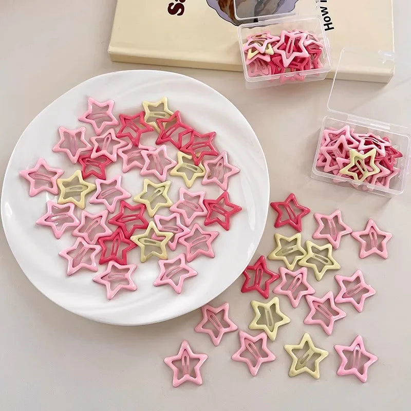 Colorful Kawaii star-shaped hair barrettes in pink, red, and yellow shades arranged on a plate and in plastic boxes
