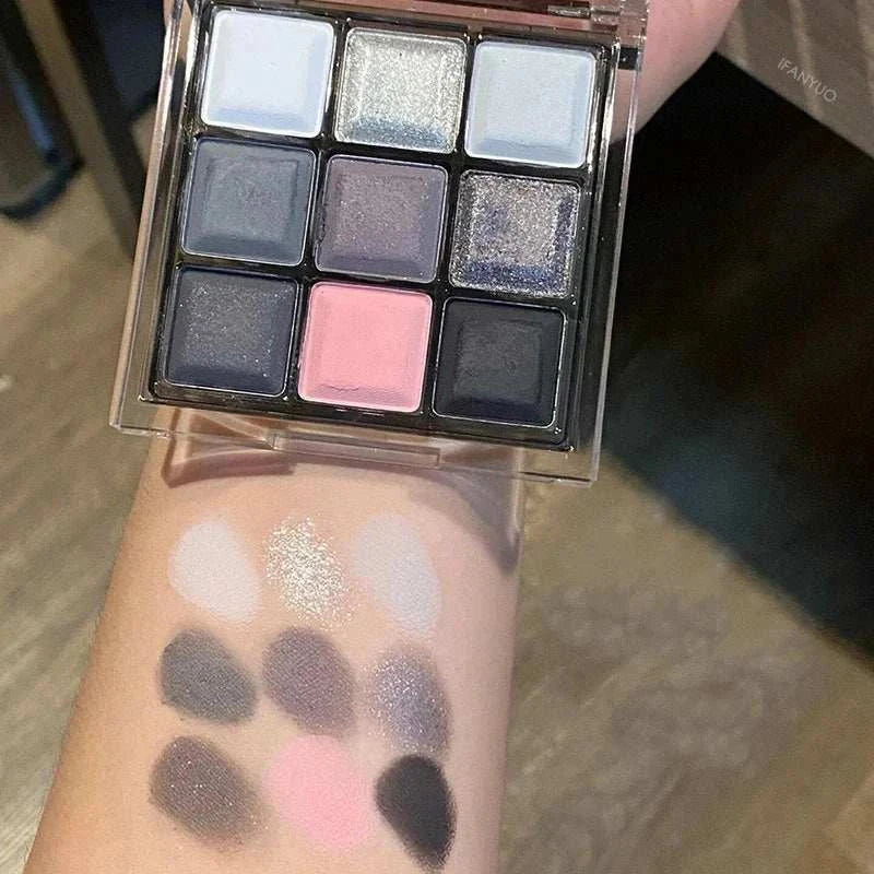 Black Pink Smoky Eye shadow palette with matte and pearlescent shades swatched on arm showing black, pink, gray, and shimmering tones.