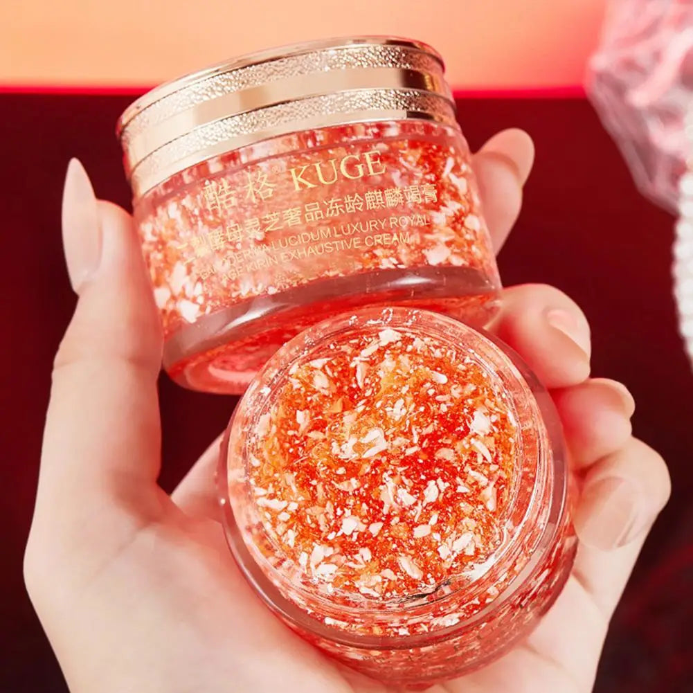 Hand holding open jar of Dragon Blood Retinol Cream moisturizer with red and gold shimmer, Korean skincare product for hydration and anti-aging.