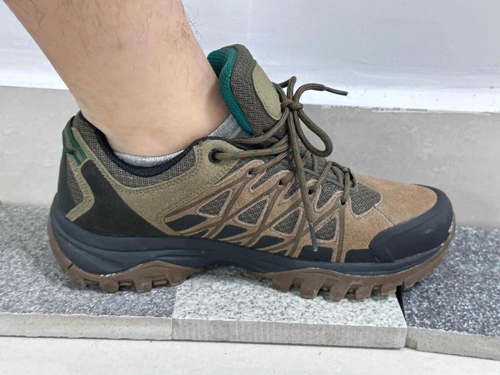 Men's Hiking Shoes in brown and black with rugged sole and breathable mesh design worn on foot for outdoor use