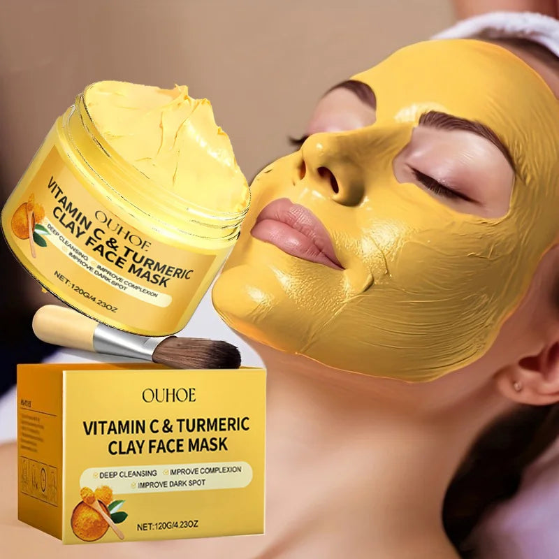 Vitamin C and Turmeric Exfoliating Facial Mask applied on woman’s face with product jar and brush beside her, brightening and deep-cleansing skincare treatment