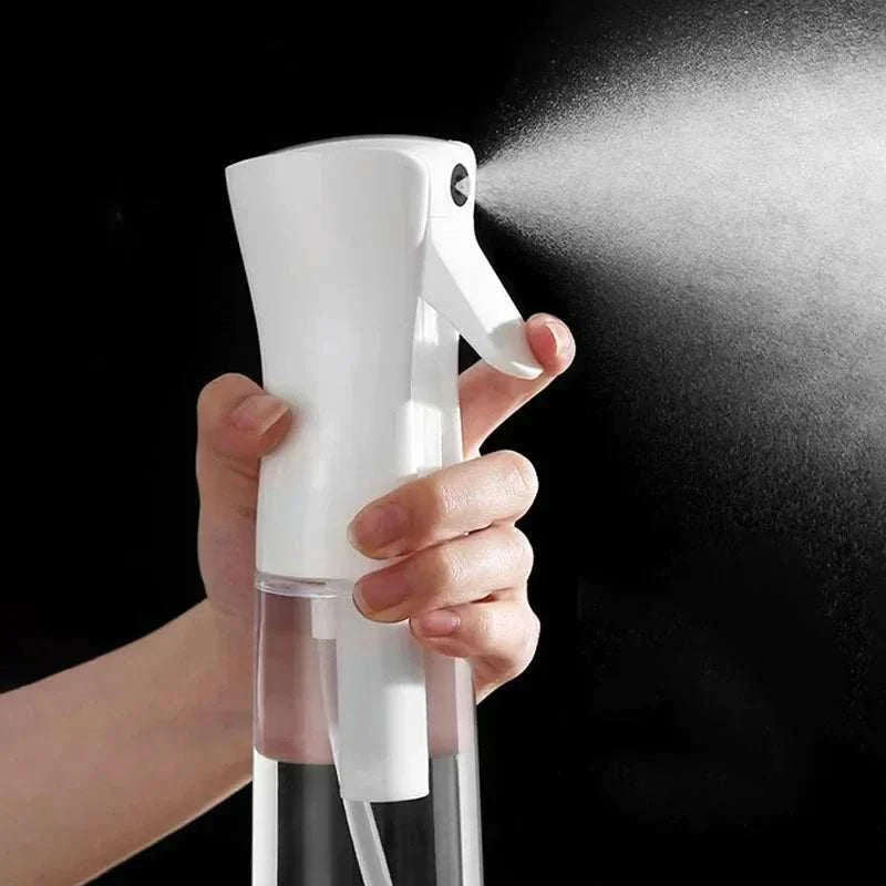 Hand holding a white high pressure mist spray bottle releasing fine mist spray against a black background
