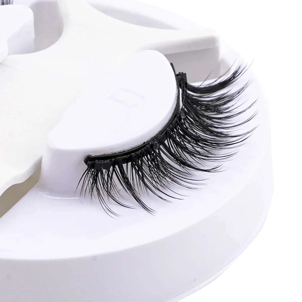 Close-up of a single black hot magnetic eyelash on a white plastic holder, showcasing soft and voluminous synthetic fibers.