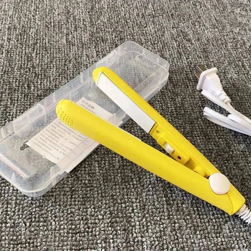 Compact yellow mini flat iron for travel with white plates and a carrying case on a gray carpet.