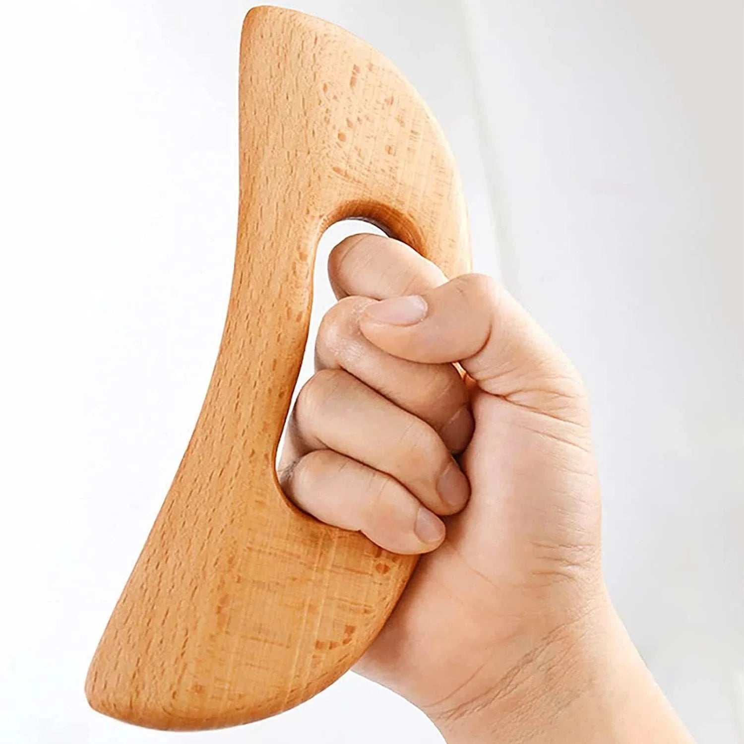 Hand holding ergonomic wooden Gua Sha tool for body massage and anti-cellulite therapy