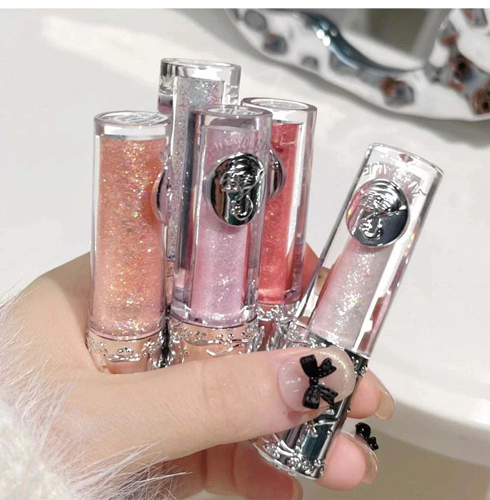 Balletism liquid eyeshadow tubes in shimmering pink, peach, and silver shades with elegant silver caps held in hand