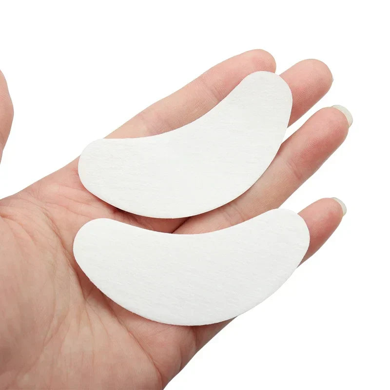 Pair of white eyelash extension gel eye pads resting on a hand, designed for under-eye protection during lash treatments.