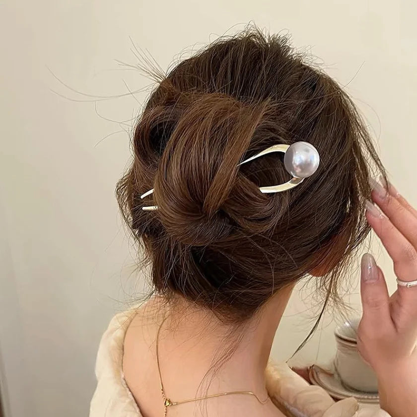 Woman with brown hair styled in an elegant bun secured with pearl U-shaped hairpins