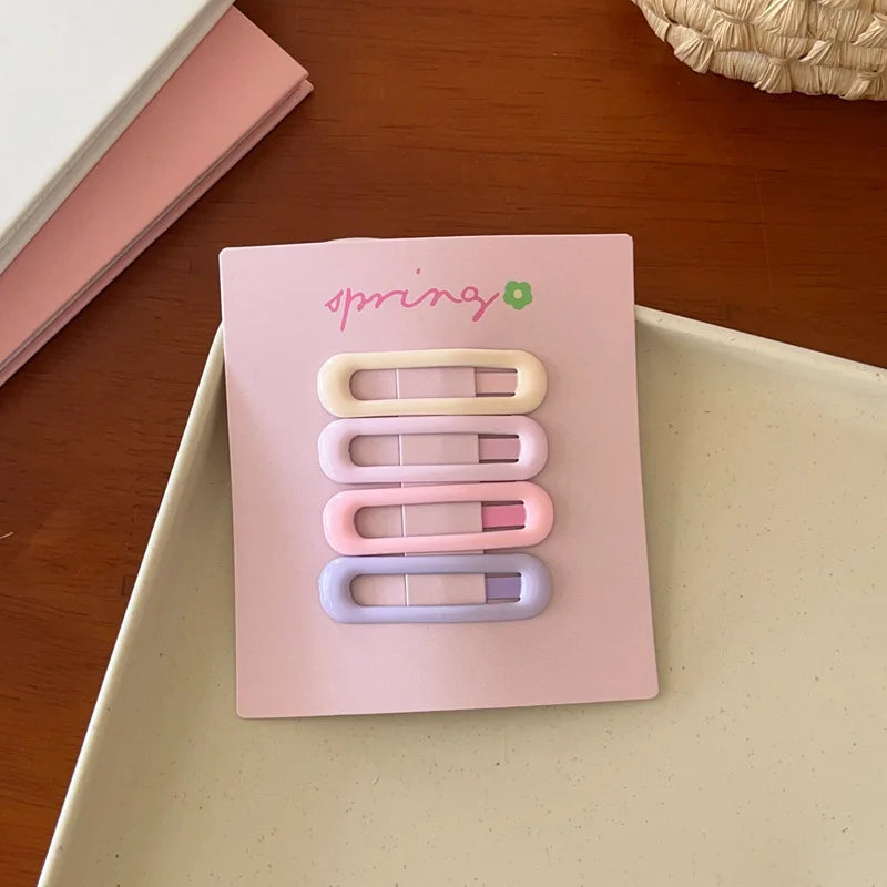 Set of 4 cute colorful geometric mini hair clips in pastel shades on a pink card