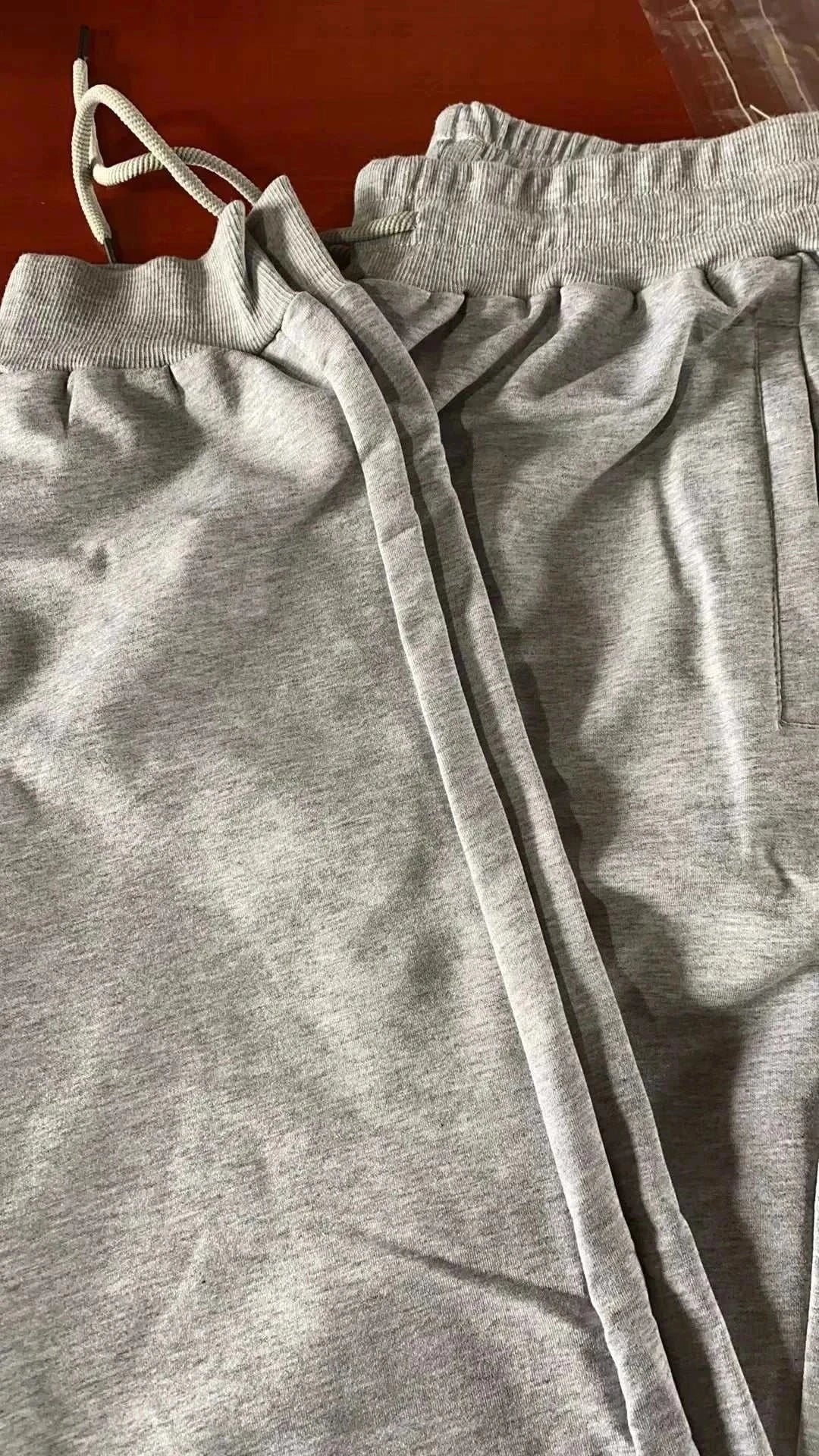 Gray men's training jogger sweatpants with elastic waistband and drawstring on a wooden surface