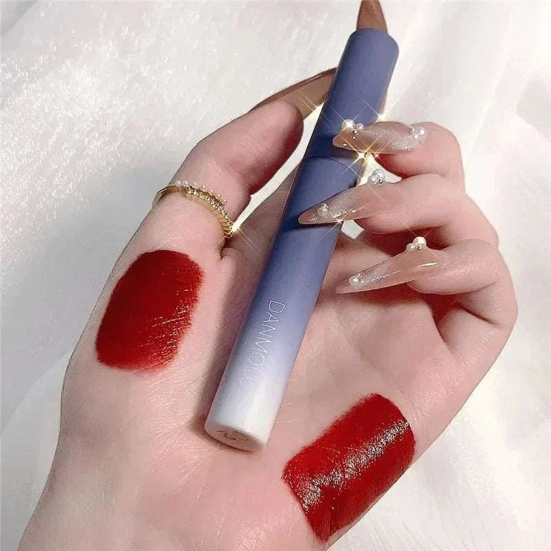 Matte lipstick set with bold red shades and sleek blue packaging held on hand with glittery nails